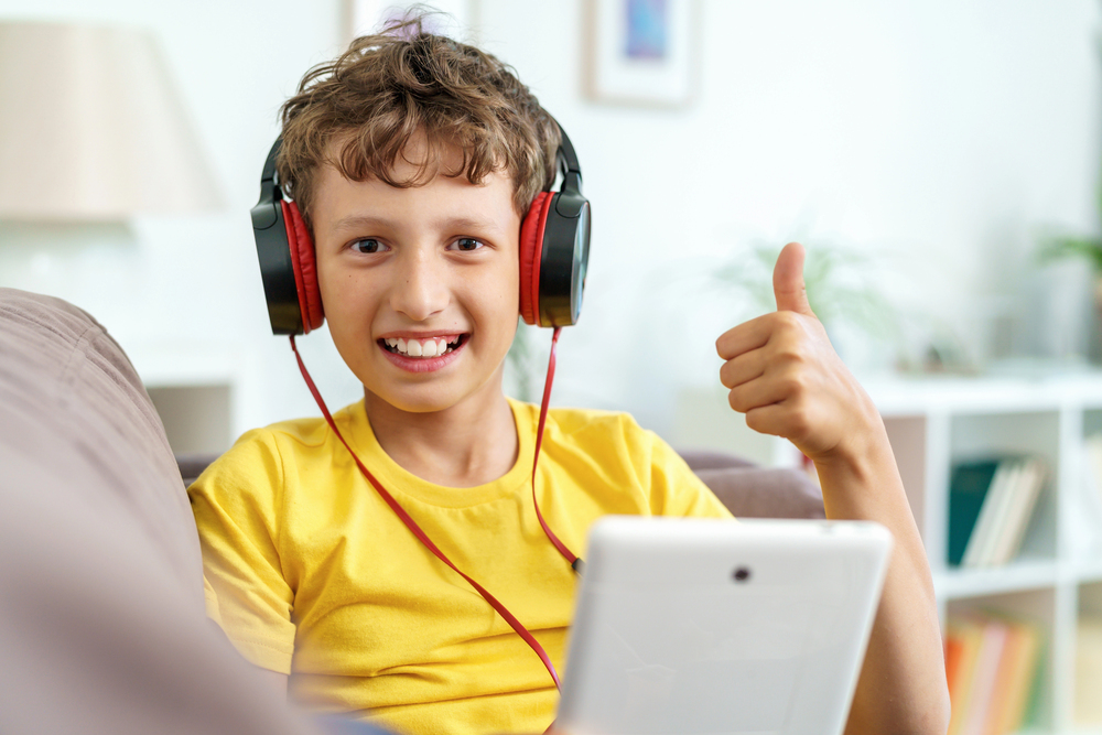 Thumbs up image of boy in yellow t shirt and wearing headphones for handwriting lessons page